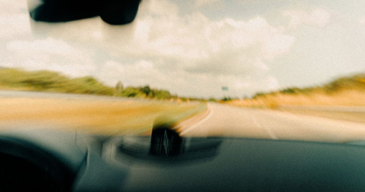 Dynamic blurred image from a vehicle's windshield capturing a rural road in motion.