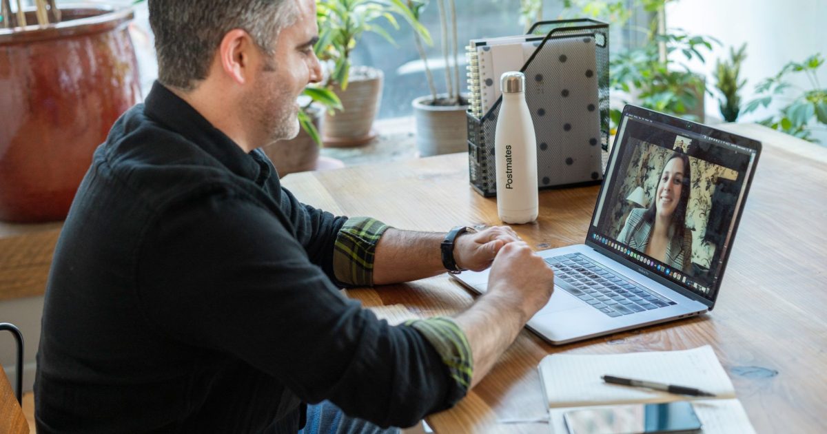 A man participates in a virtual meeting from his home workspace, focusing on remote work.