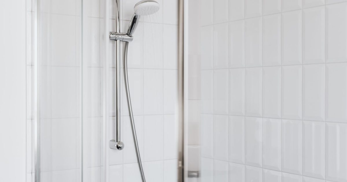 Stylish shower setup with chrome fixtures and clean white tiles.