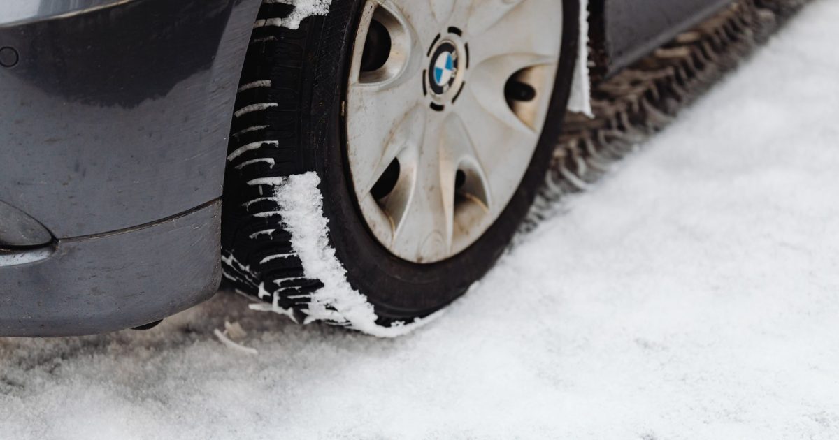 Close-up of a car's tire on a snowy road, highlighting the winter season conditions.