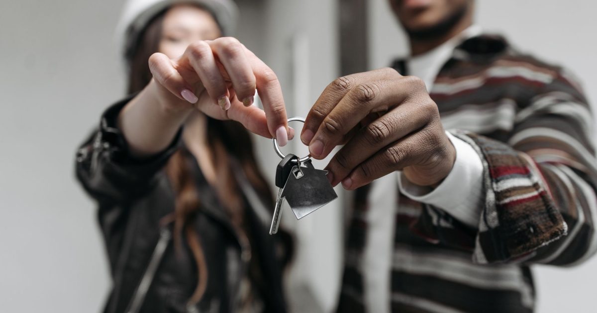 Close-up of a couple joyfully holding keys to their new home, symbolizing new beginnings and home ownership.