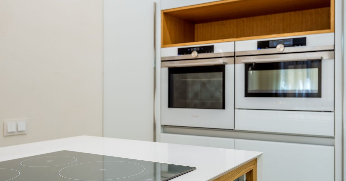 Interior of contemporary light kitchen with white ovens and clean new stove in modern apartment