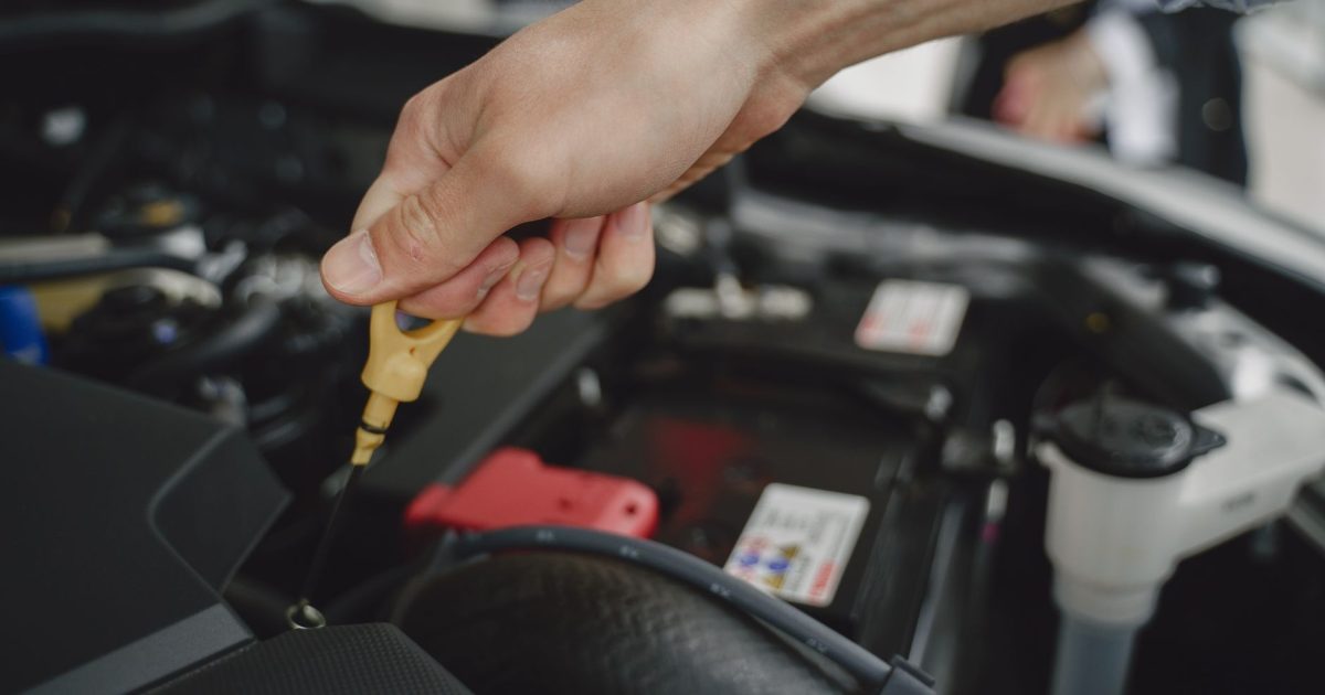 Hand checking oil dipstick in a car engine bay for maintenance and diagnostics.